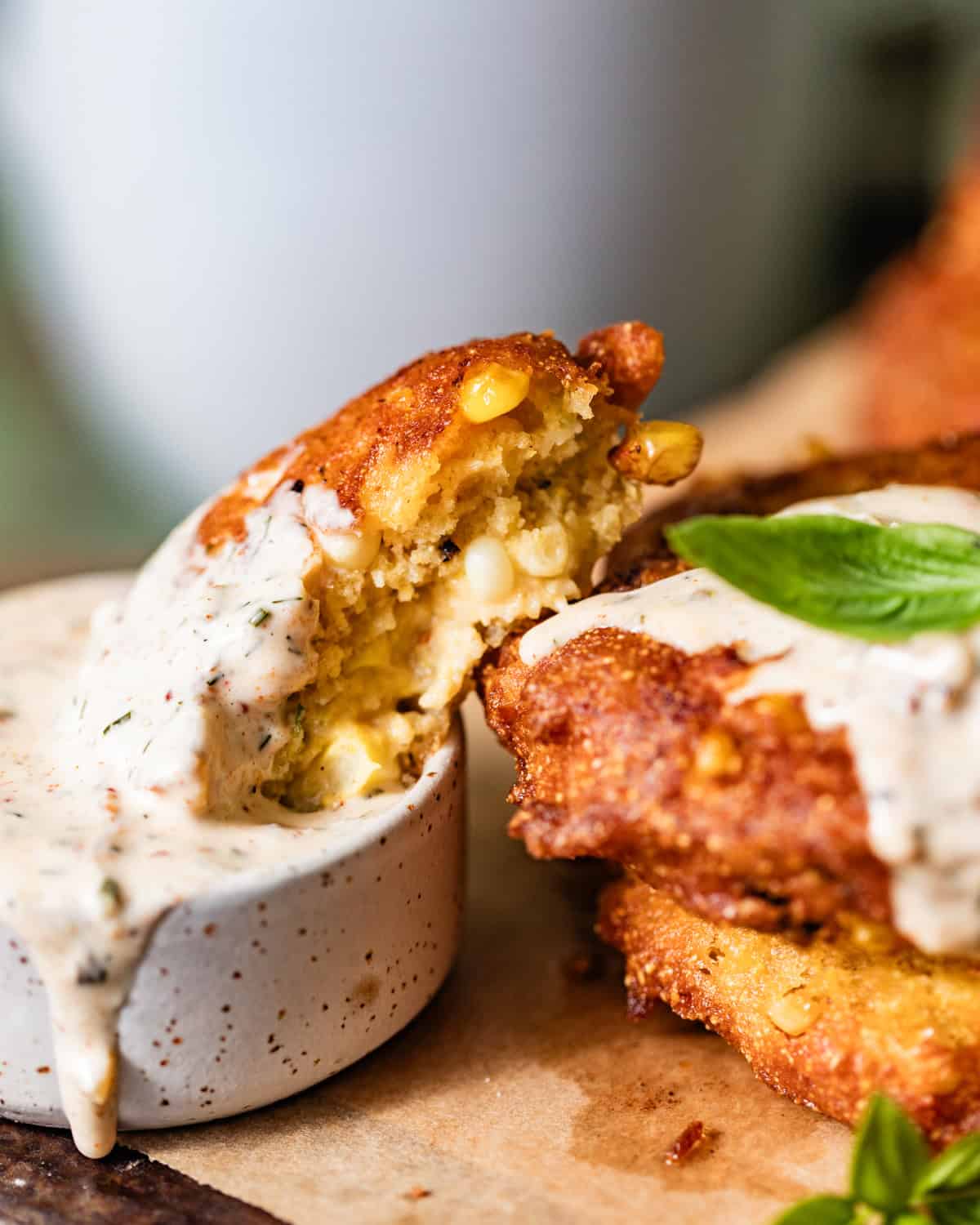 a corn fritter cut in half and dipped into a bowl of cajun remoulade.