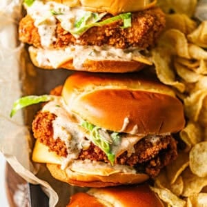fried fish sandwiches in a serving tray with a side of potato chips.