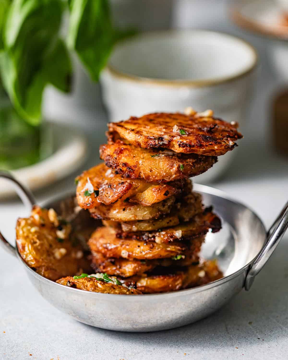 parmesan smashed potatoes in a serving bowl stacked on top of one another.