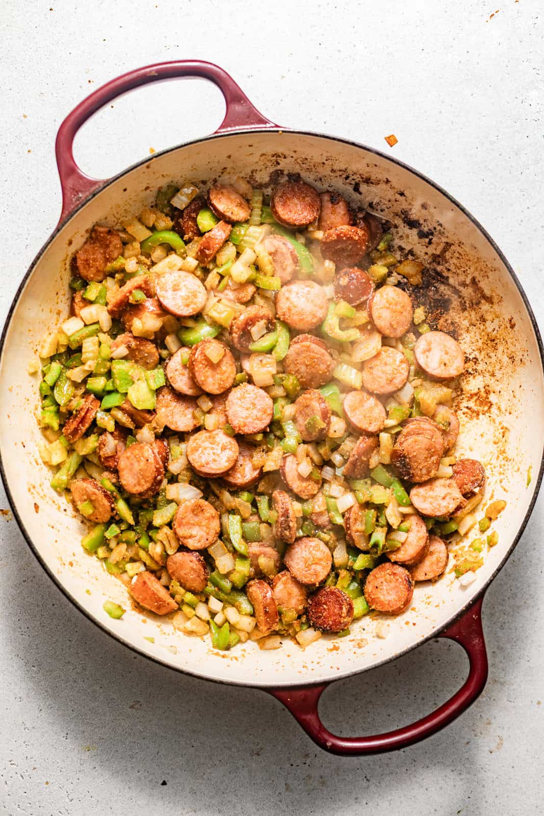 seared sausages and vegetables in a skillet.