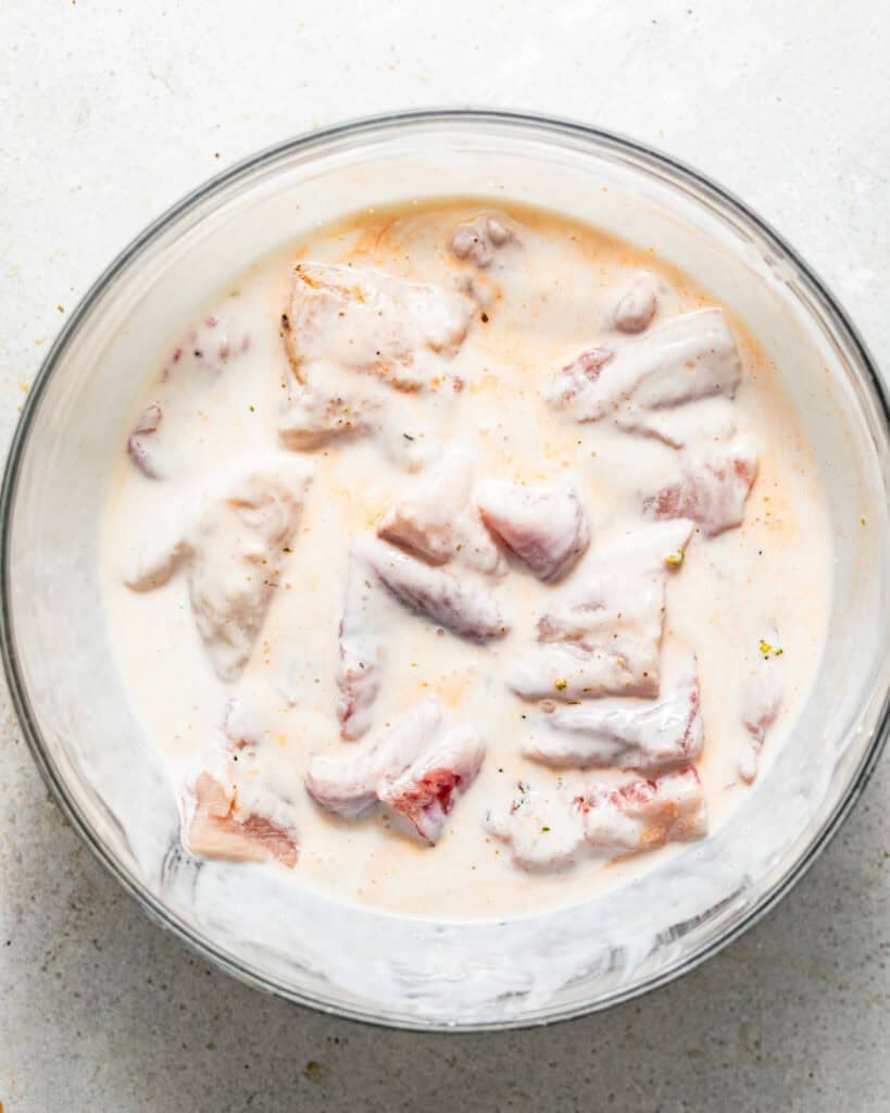 catfish nuggets marinating in buttermilk and hot sauce.