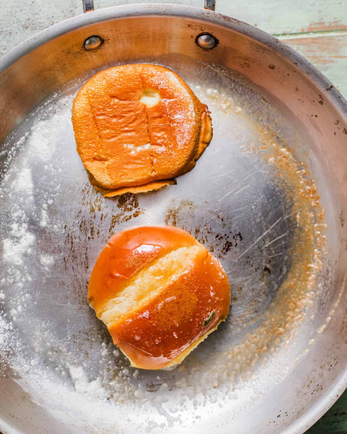 brioche buns in a pan being toasted in melted butter.