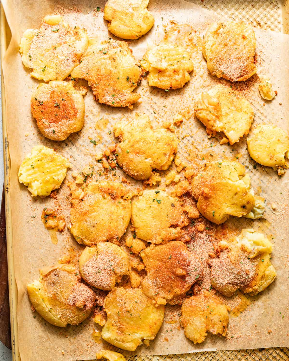 baby potatoes smashed on a baking sheet and drizzled with olive oil and seasonings.