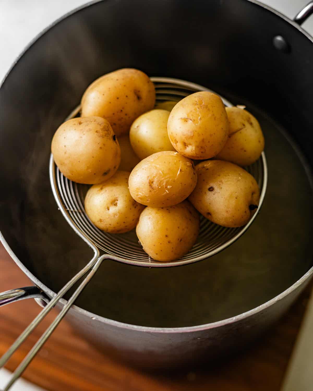 cooking baby potatoes coming out of a pot of boiling water.