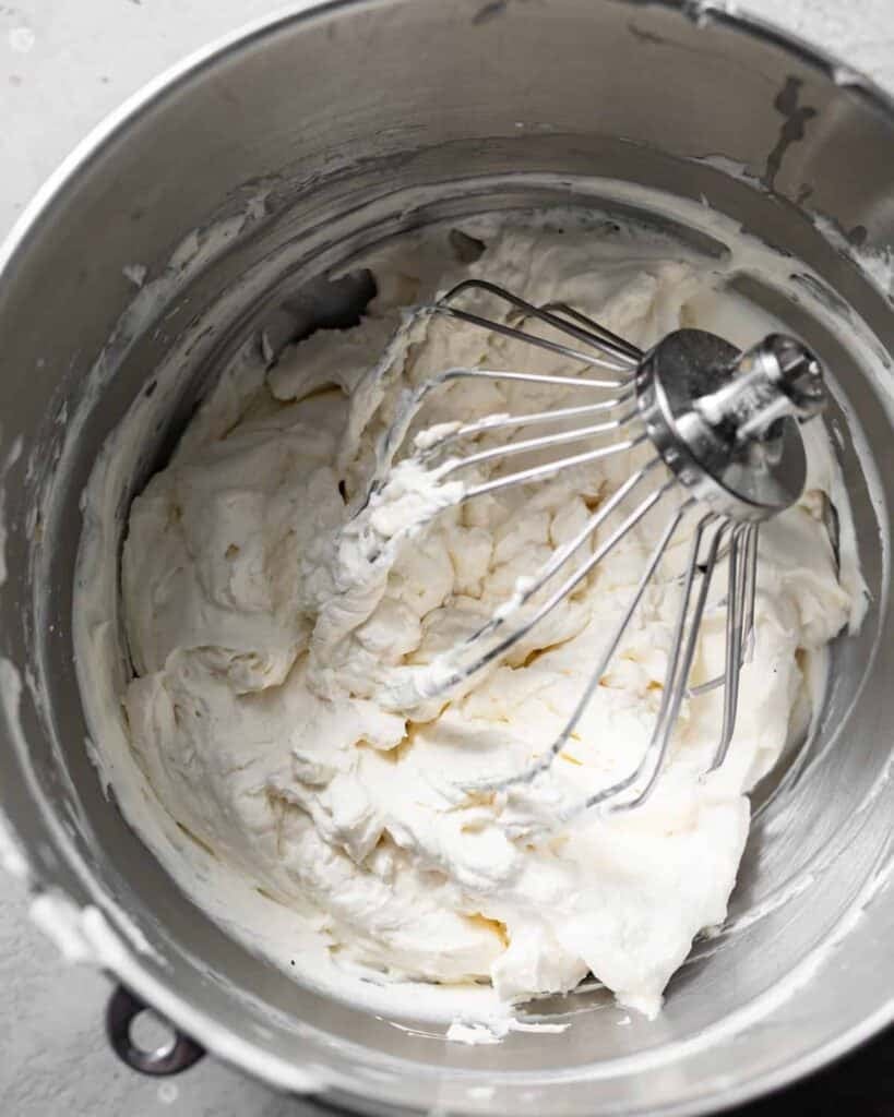 lemon cream cheese frosting mixed together in the bowl of a stand mixer.