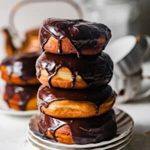 Stack of homemade chocolate glazed yeast donuts with glossy chocolate glaze dripping down the sides.