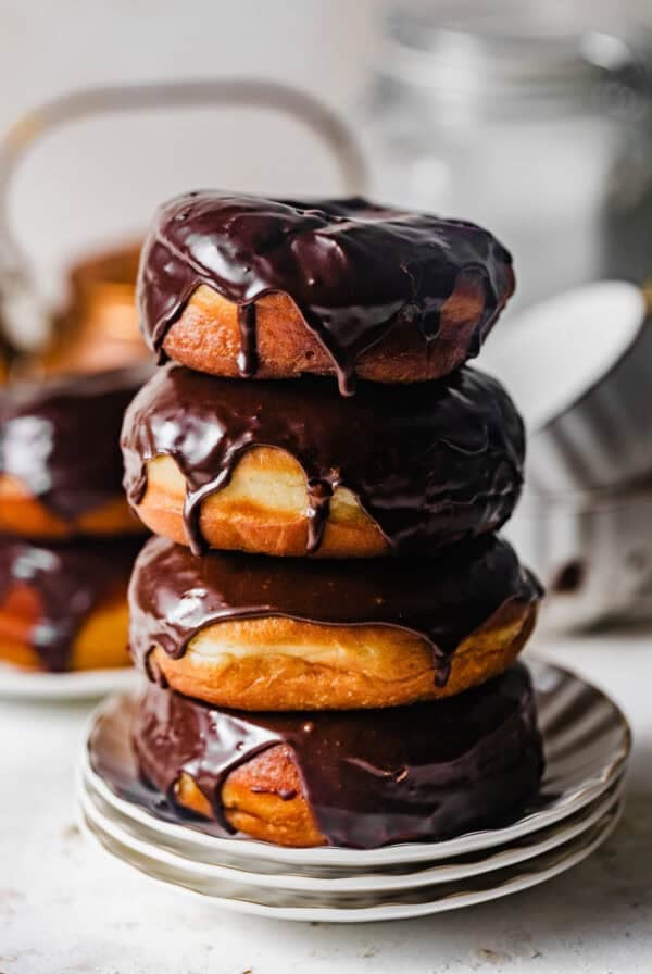 Stack of homemade chocolate glazed yeast donuts with glossy chocolate glaze dripping down the sides.