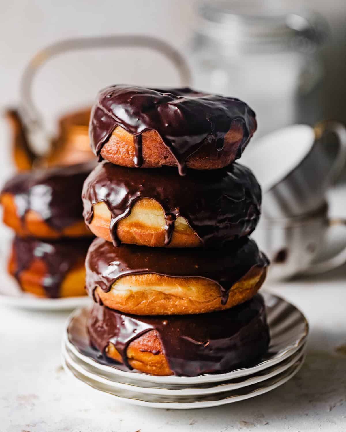 Stack of homemade chocolate glazed yeast donuts with glossy chocolate glaze dripping down the sides.
