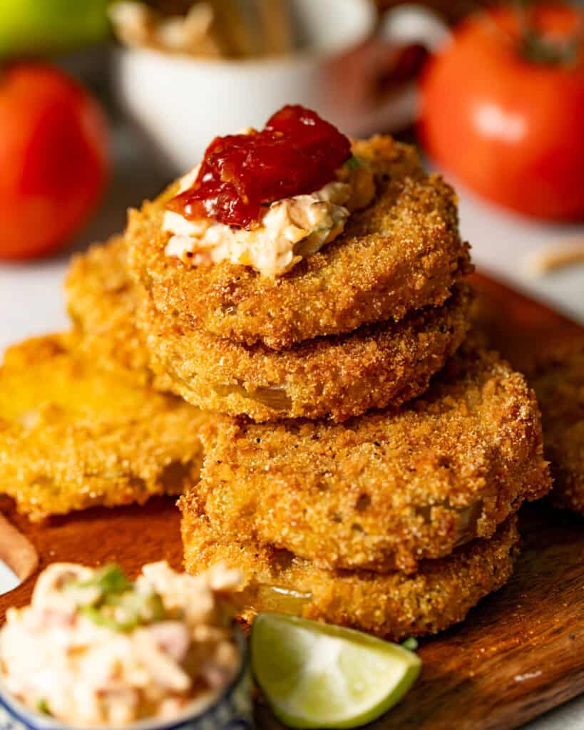 fried green tomatoes stacked on top of one another with pimento cheese on top.