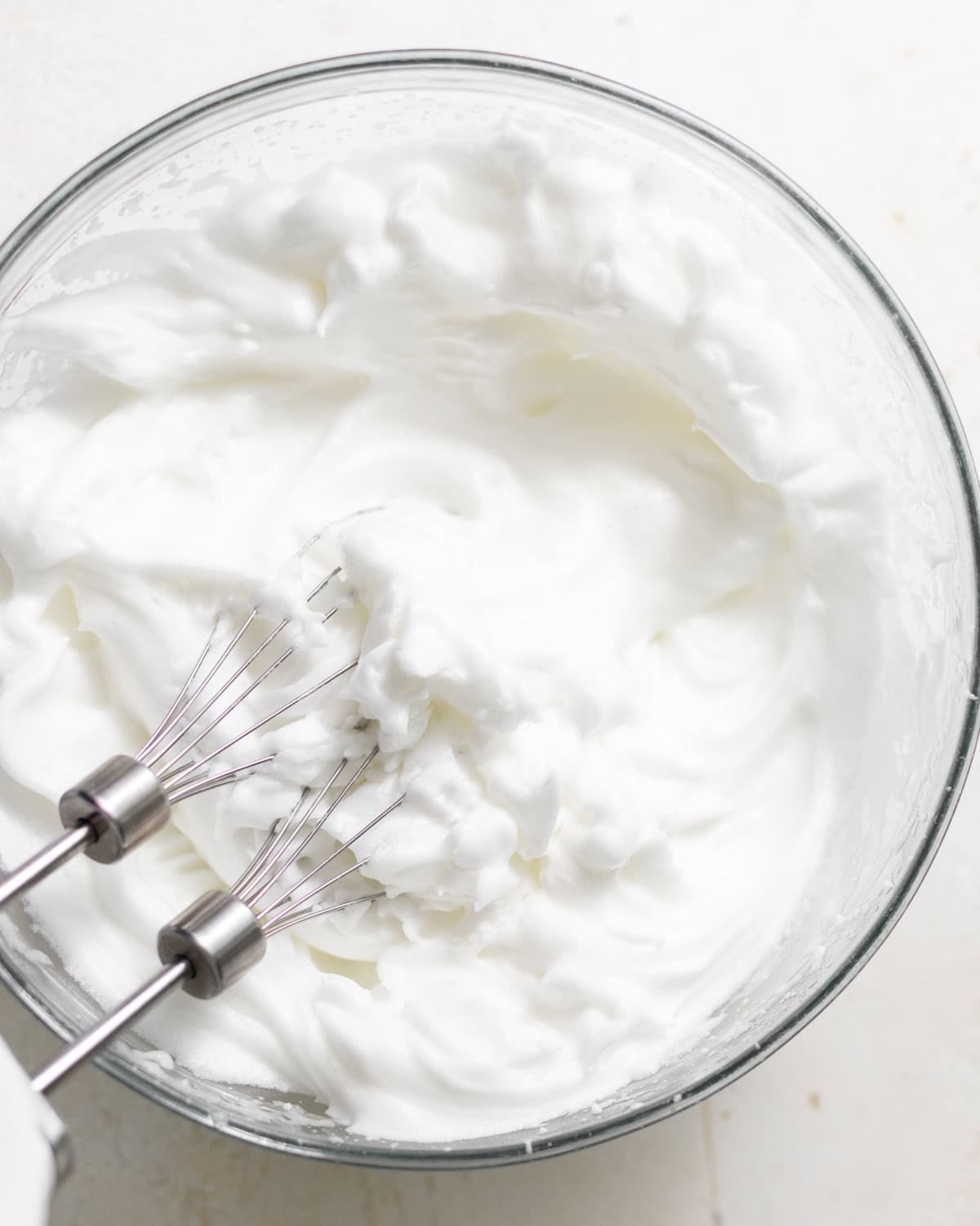 Egg whites beaten to stiff peaks in a clean glass bowl.