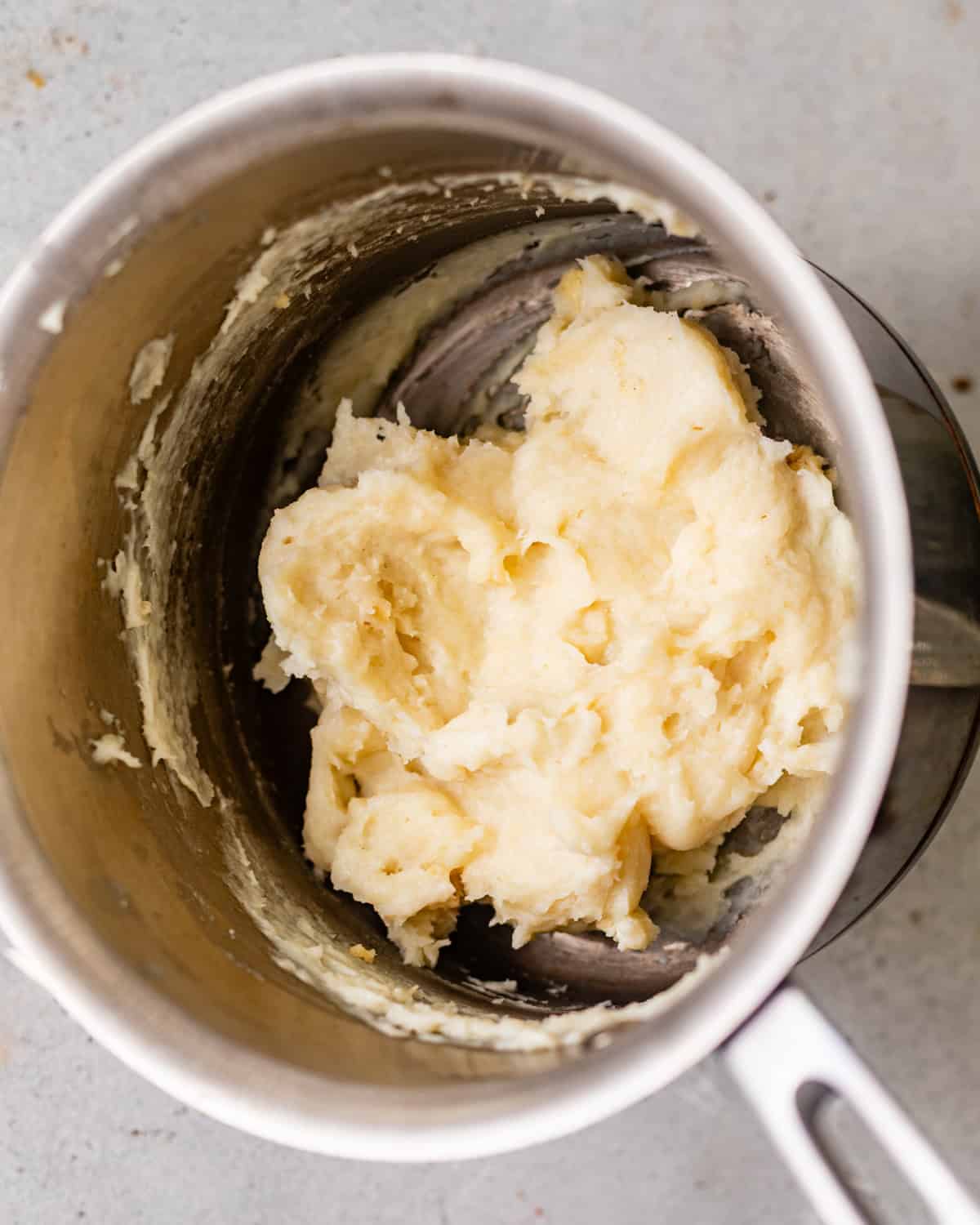 Thick tangzhong paste made with milk and bread flour in a small saucepan for homemade yeast donuts.