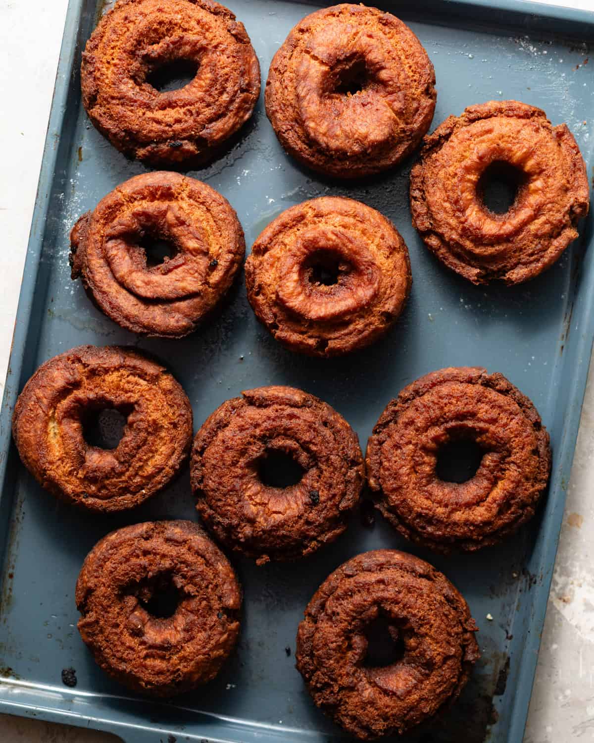 fried maple donuts on a baking sheet.