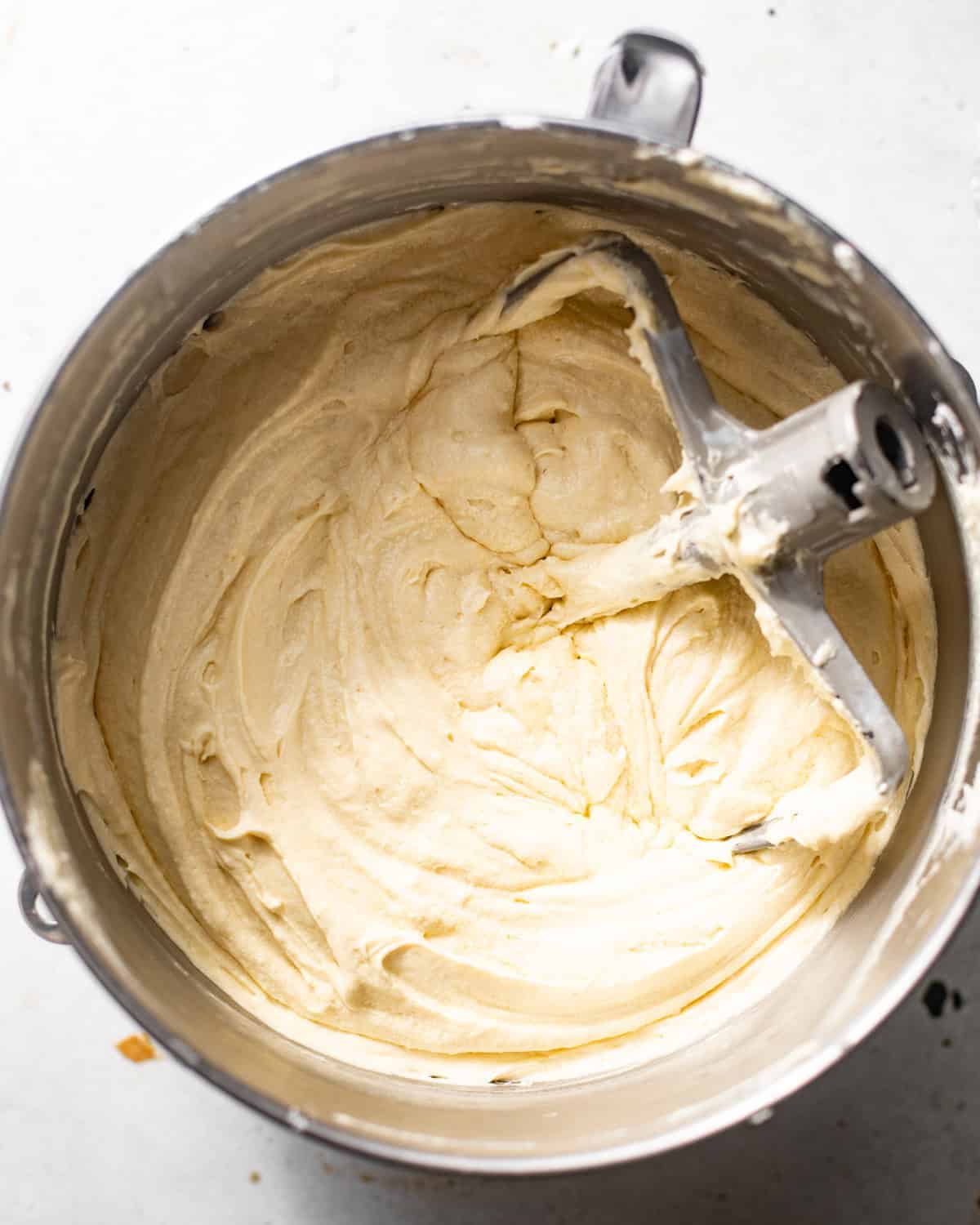 milk and honey cake batter in the bowl of a stand mixer with the paddle attachment.