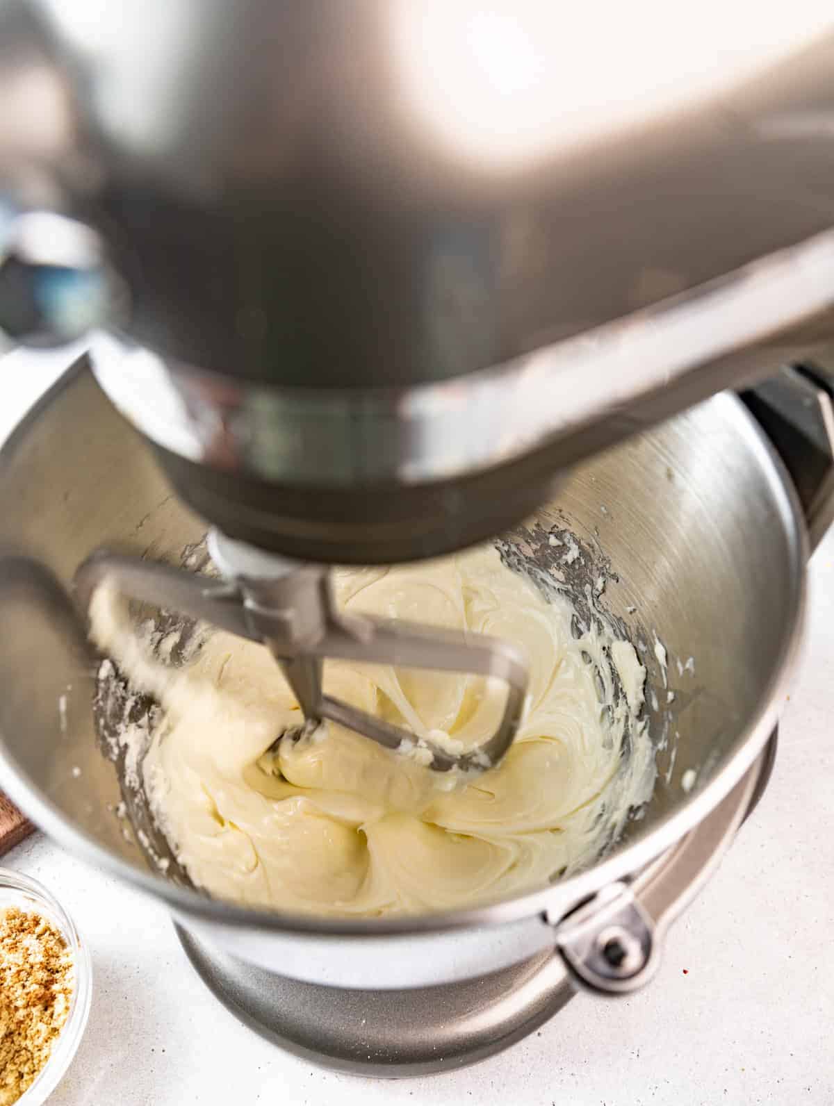 cheesecake batter in the bowl of a stand mixer fitted with the paddle attachment.