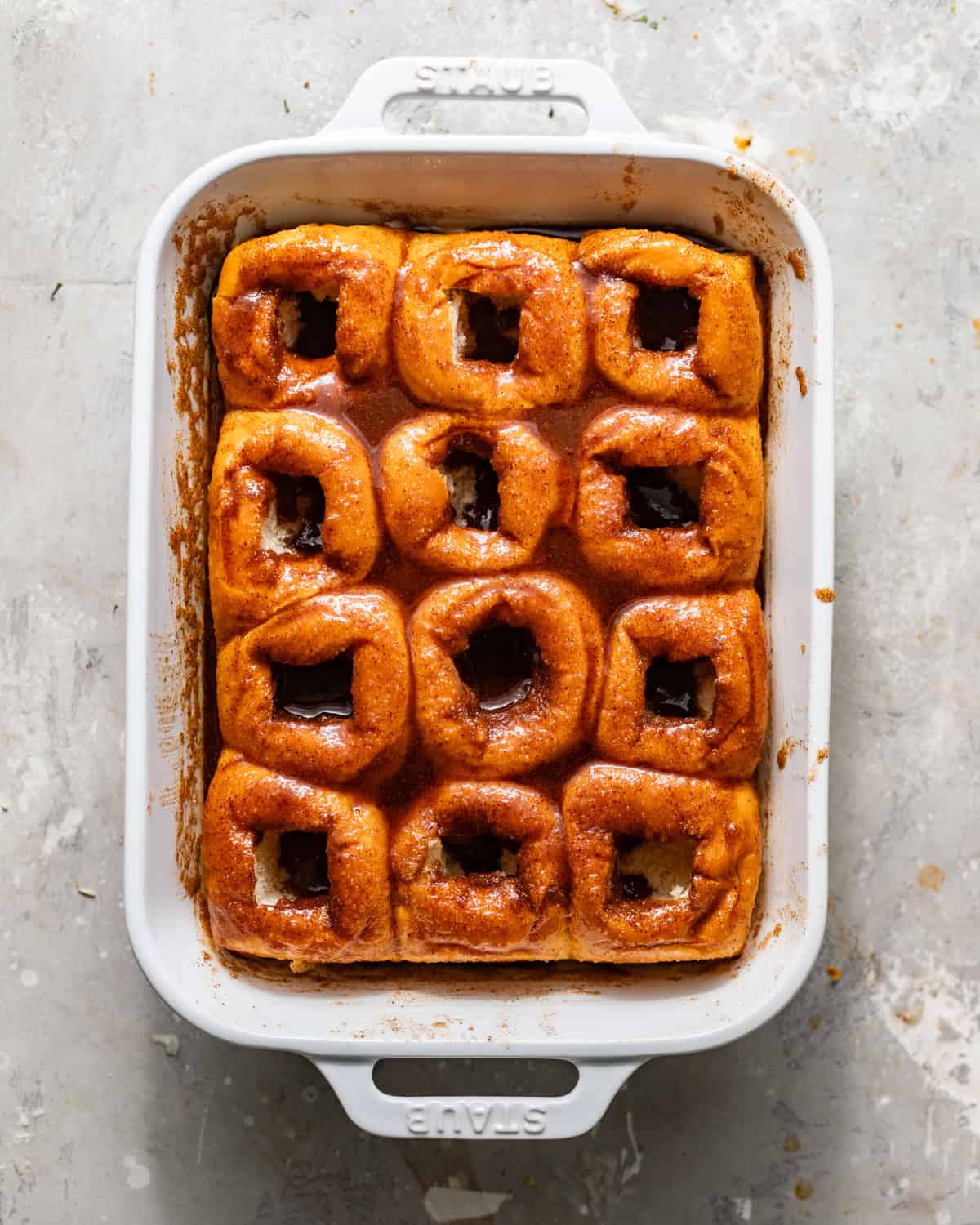 hawaiian rolls in a baking dish with the center of the rolls cut out and covered in cinnamon roll filling.
