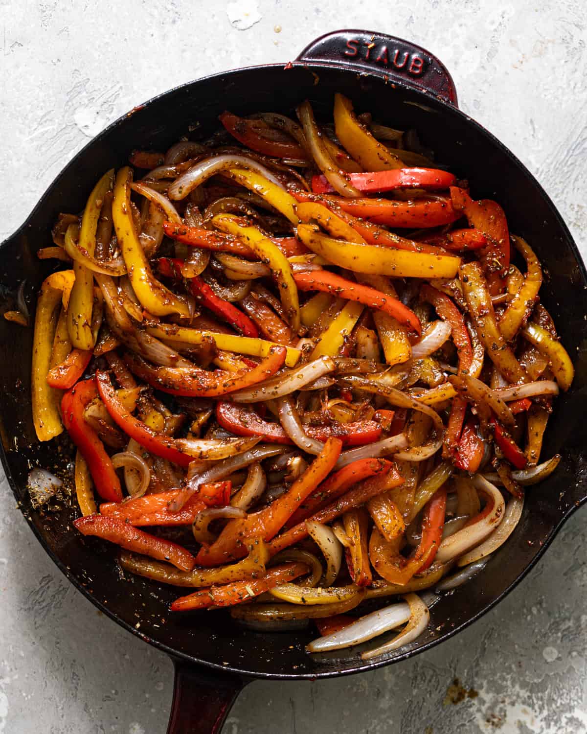 sliced onions and bell peppers cooked in a skillet and tossed in Italian seasoning.
