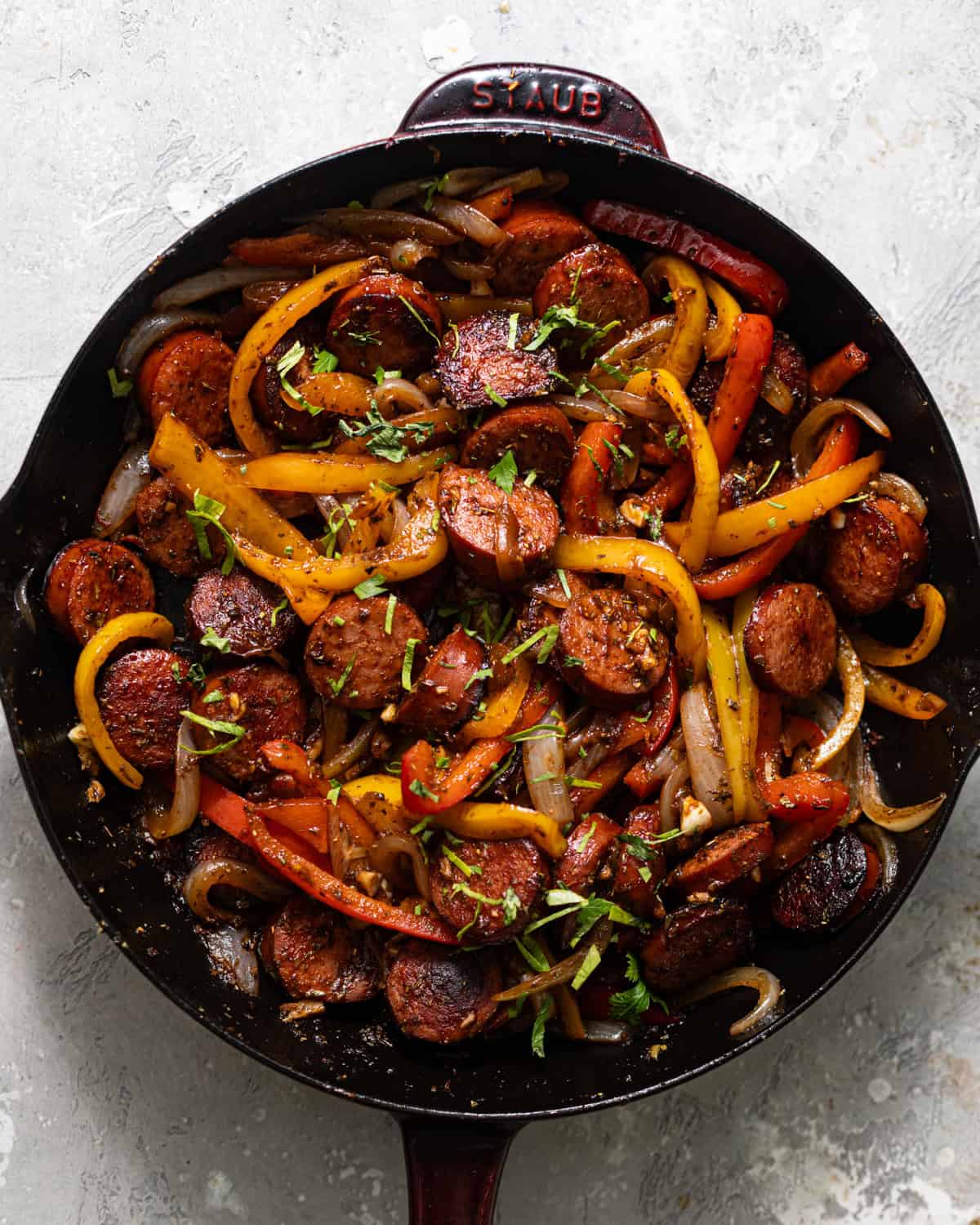 sausage, peppers, and onions cooked in a skillet.