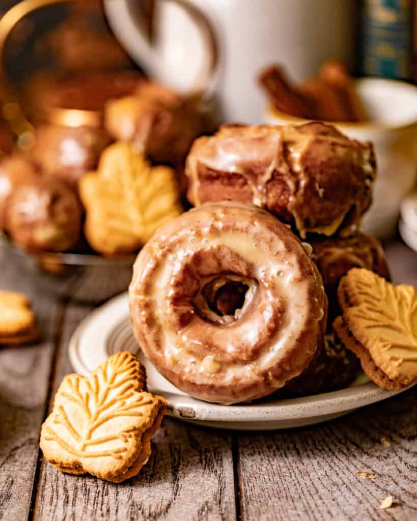 maple donuts on a plate with a small maple cookie in front of it.