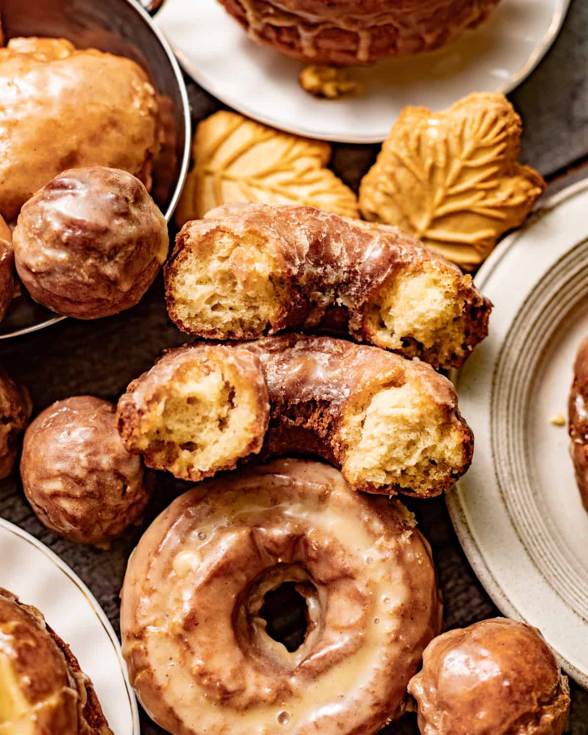 Glazed maple donuts with crisp golden edges and a soft, cakey interior, including one donut broken open to show the crumb.