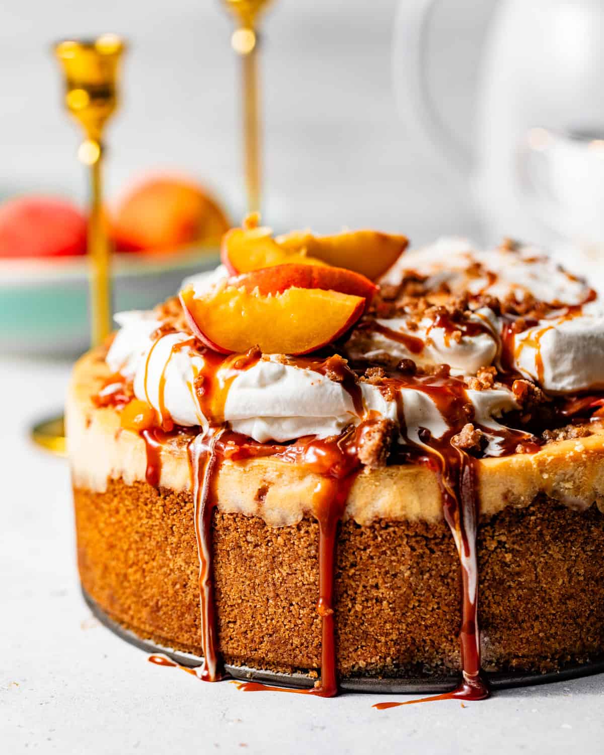 peach cobbler cheesecake topped with whipped cream and caramel sauce.