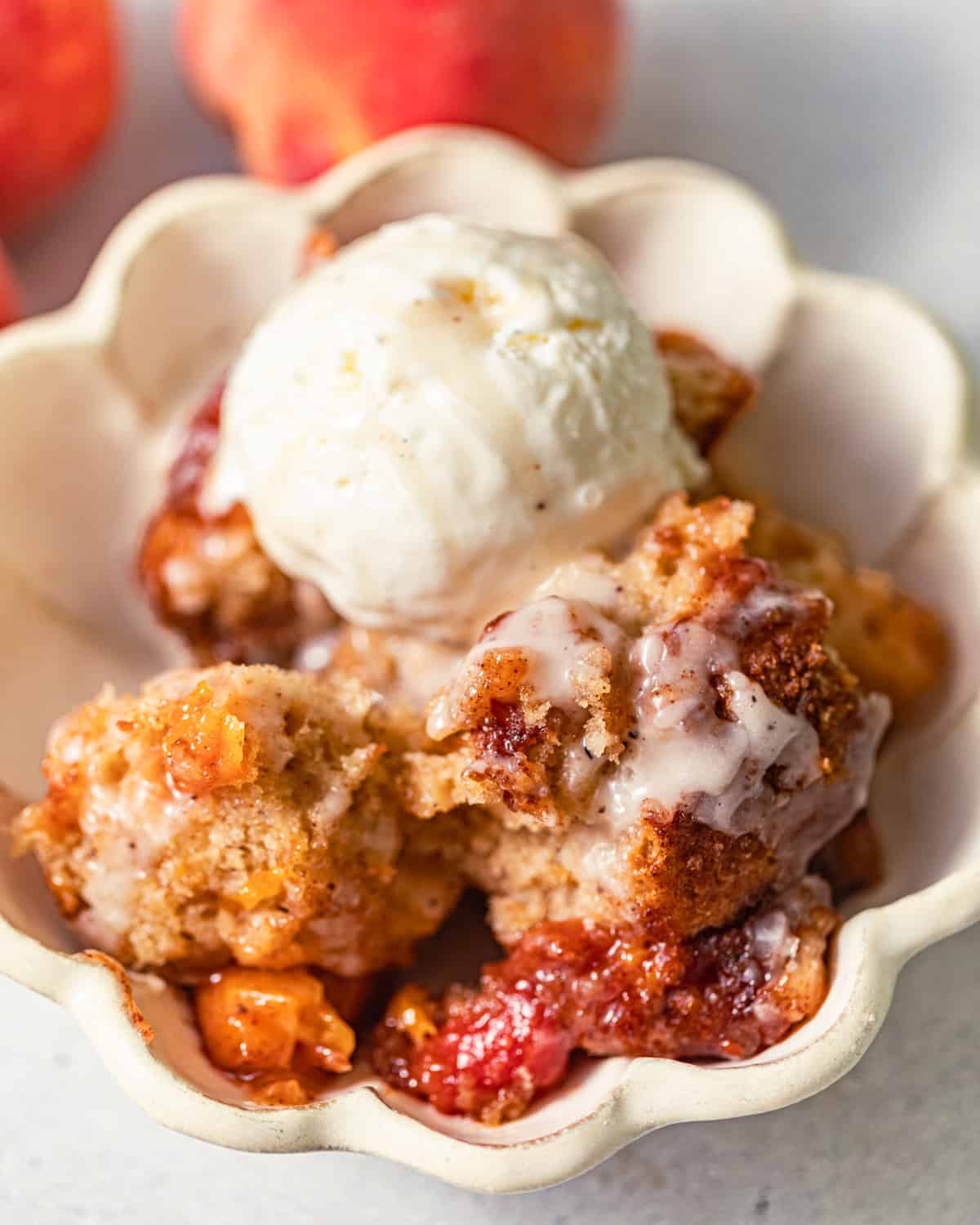 peach fritter cake in a bowl with a scoop of ice cream on top.