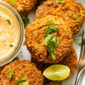 golden salmon croquettes garnished with parsley and served with creole dipping sauce and lime.