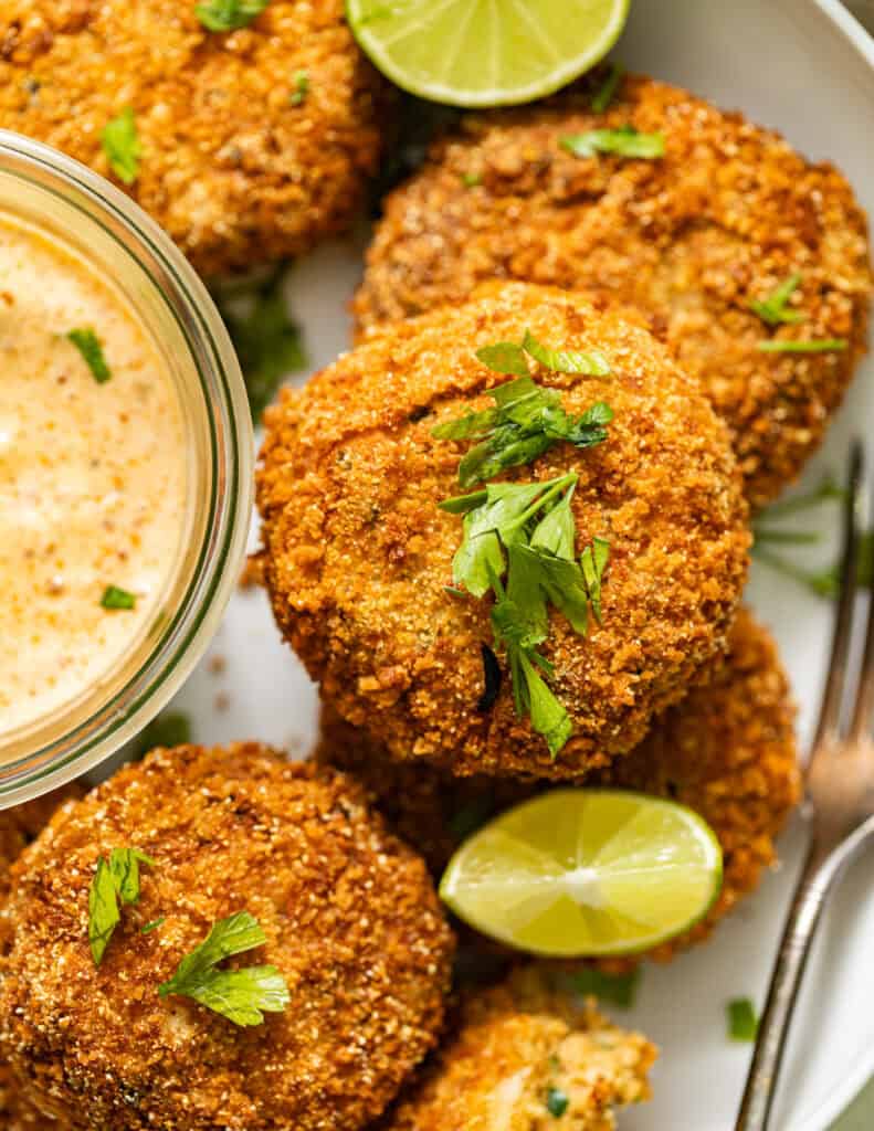 golden salmon croquettes garnished with parsley and served with creole dipping sauce and lime.