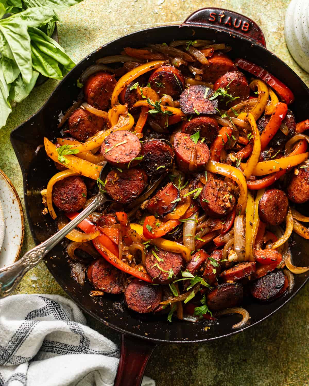 Sausage, peppers, and onions in a cast-iron skillet garnished with chopped fresh parsley.