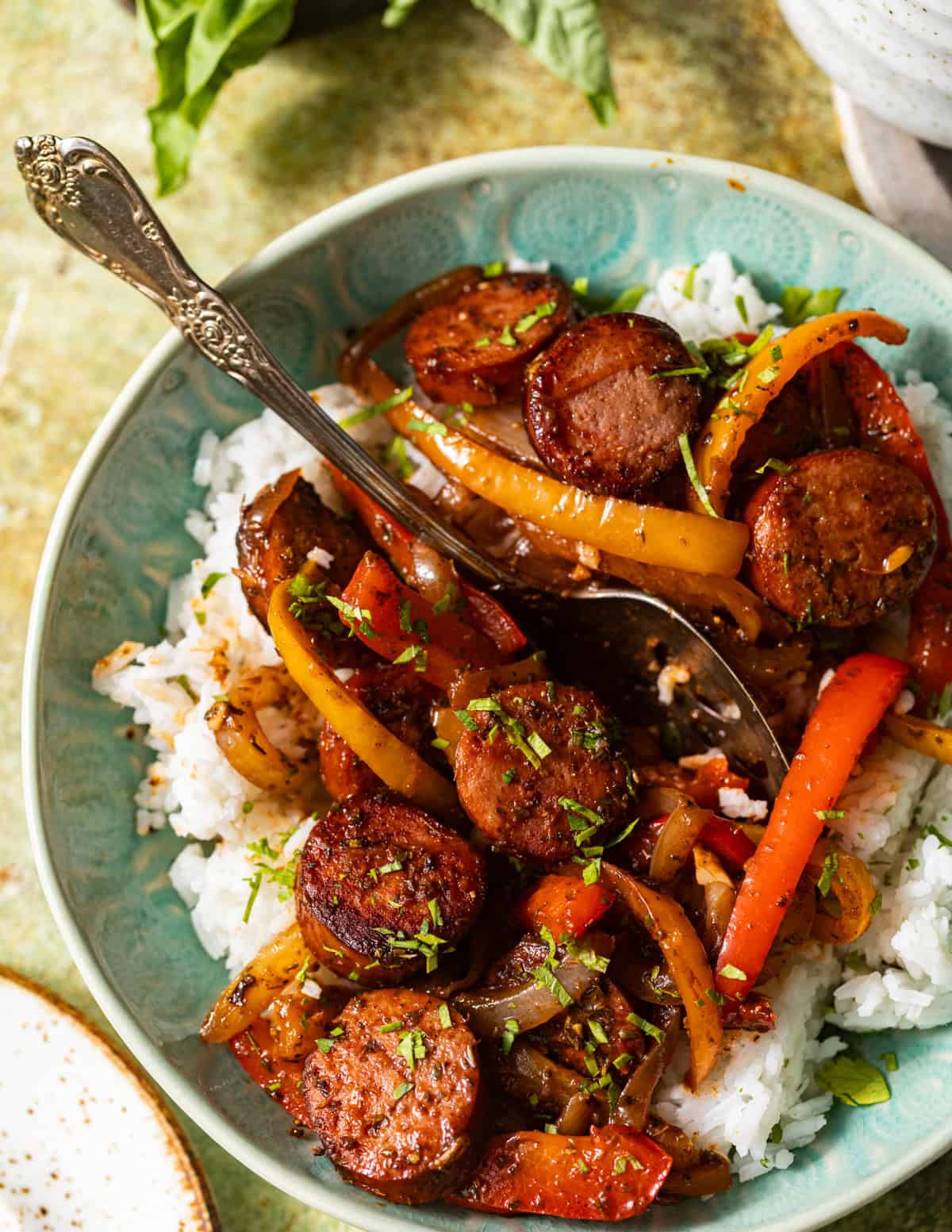 Smoked sausage, sautéed bell peppers, and onions served over white rice and garnished with fresh parsley.