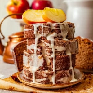 sliced apple cider donut loaf stacked on top of one another and covered in apple cider glaze.