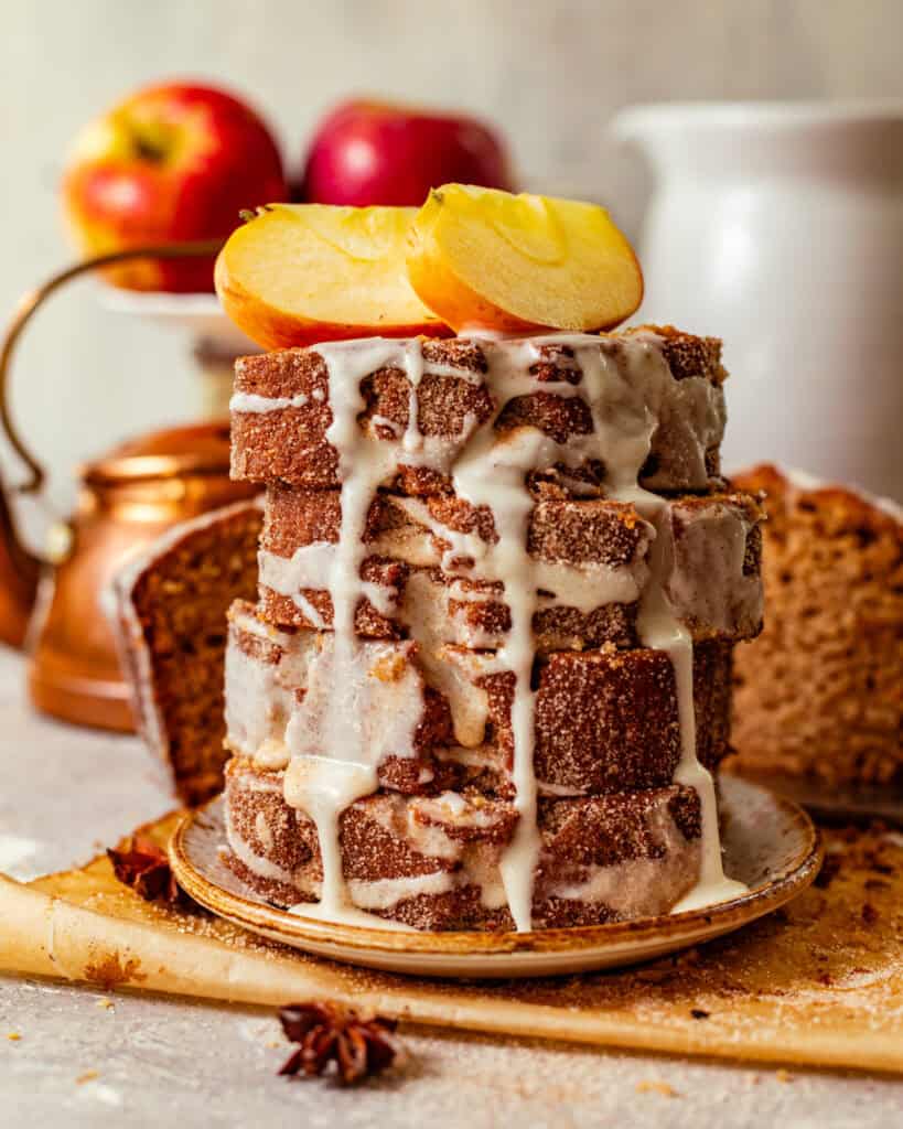 sliced apple cider donut loaf stacked on top of one another and covered in apple cider glaze.