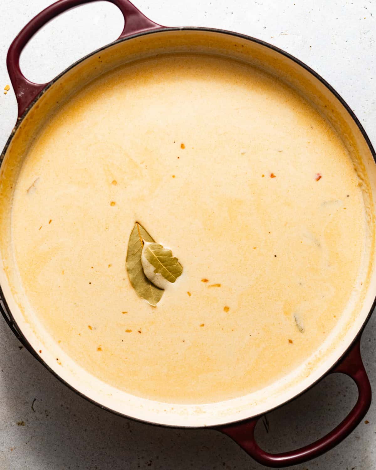she crab soup simmering in a pot with bay leaves.
