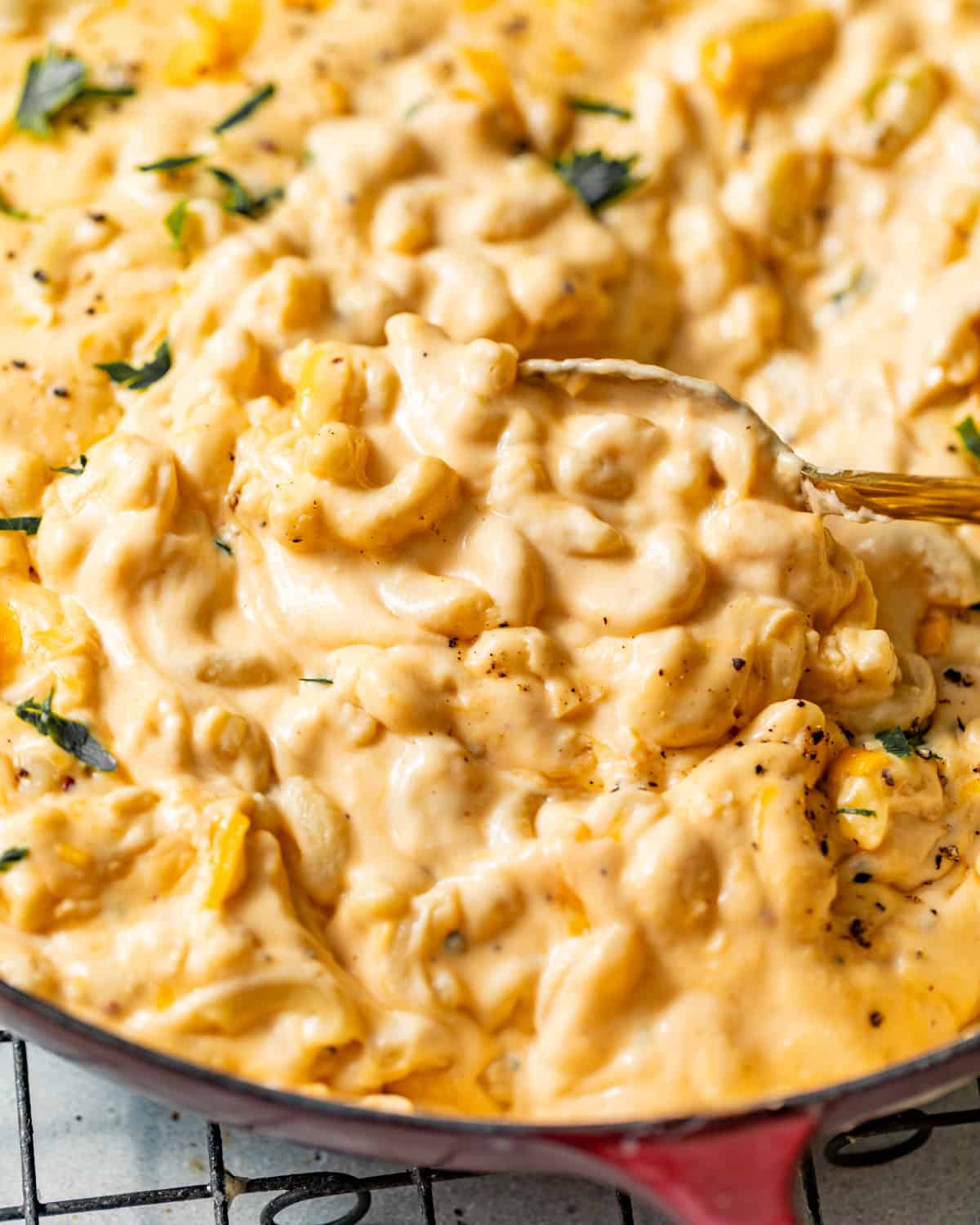 Spoonful of creamy stovetop mac and cheese lifted from a red skillet, showing the thick, velvety cheese sauce.
