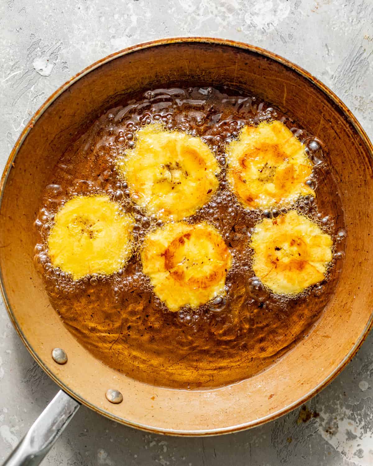 tostones frying in a skillet for the second fry.