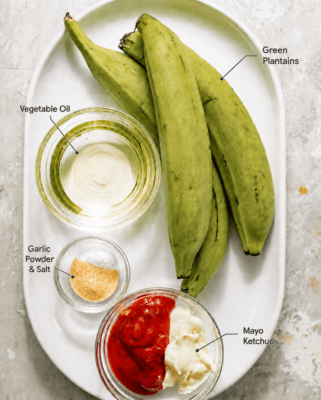 ingredients to make tostones on a plate - green plantains, vegetable oil, garlic powder, kosher salt, black pepper, mayo, and ketchup.