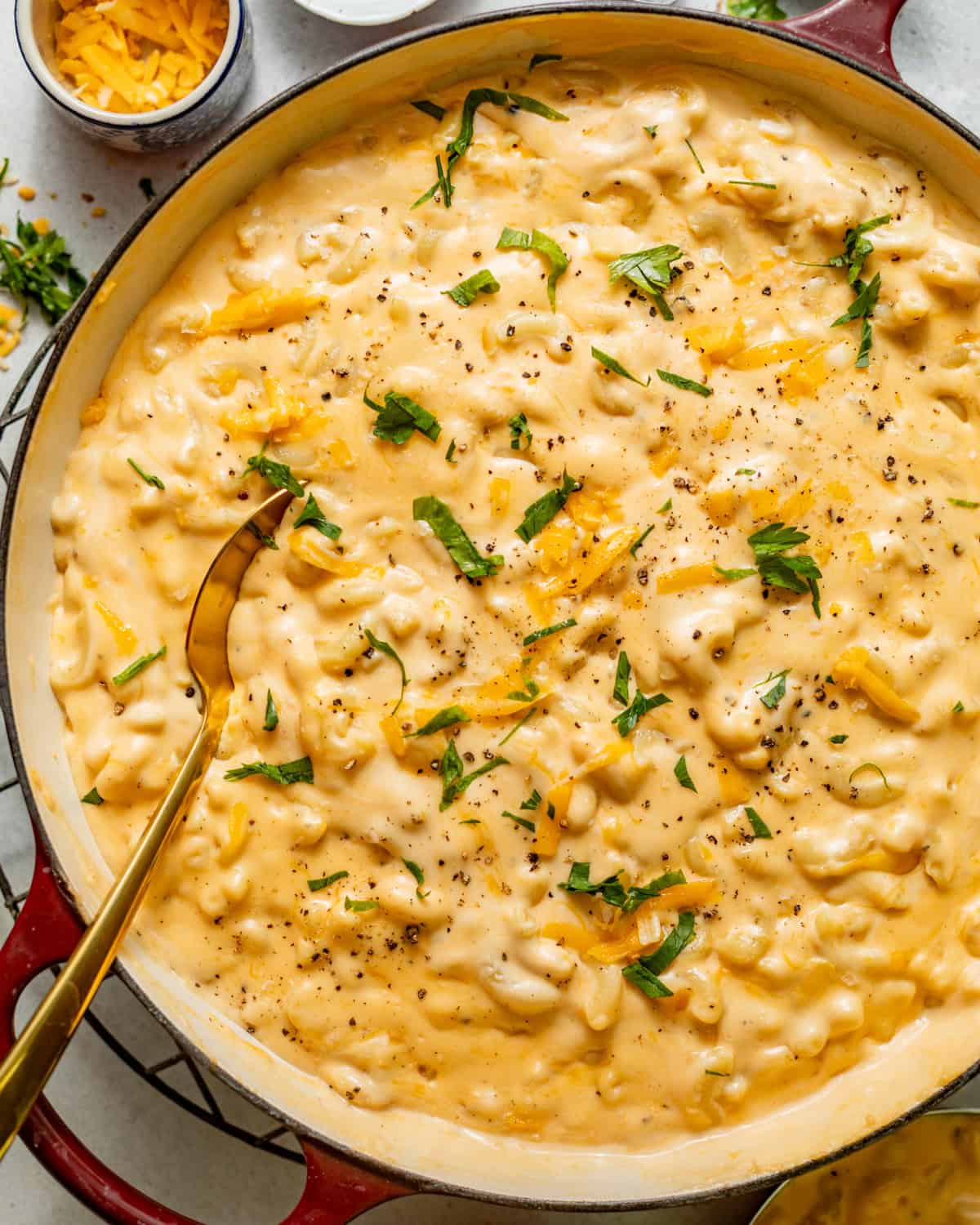 stovetop mac and cheese in a pot with a wooden spoon and garnished with parsley.