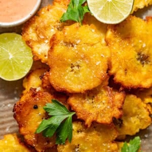 tostones on a plate with mayo ketchup in a small bowl.