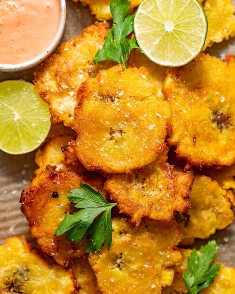 tostones on a plate with mayo ketchup in a small bowl.