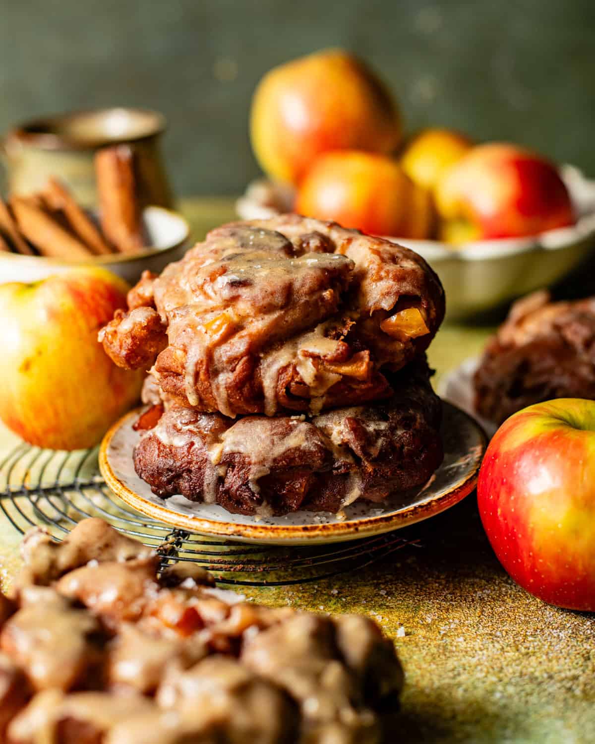 glazed apple fritter donuts stacked on top of one another on a snack plate.