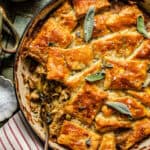 chicken pot pie with puff pastry in a pan topped with flake salt and fresh herbs for garnish.