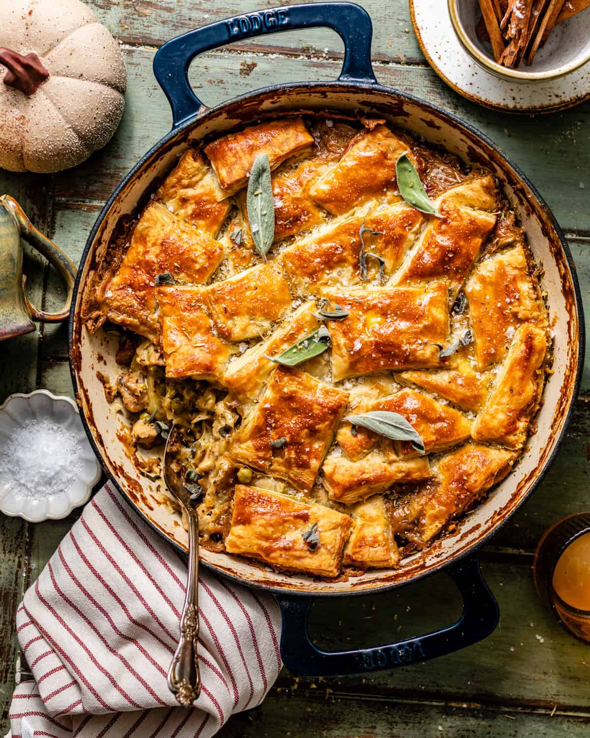 chicken pot pie with puff pastry in a pan with a spoon scooping out the smooth pot pie filling.