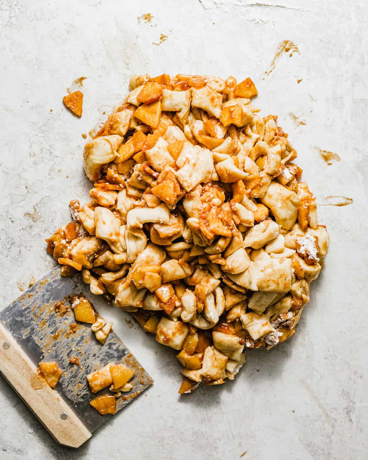 Chopped yeasted apple fritter dough mixed with cinnamon-spiced apples and gathered together before shaping into individual fritters.