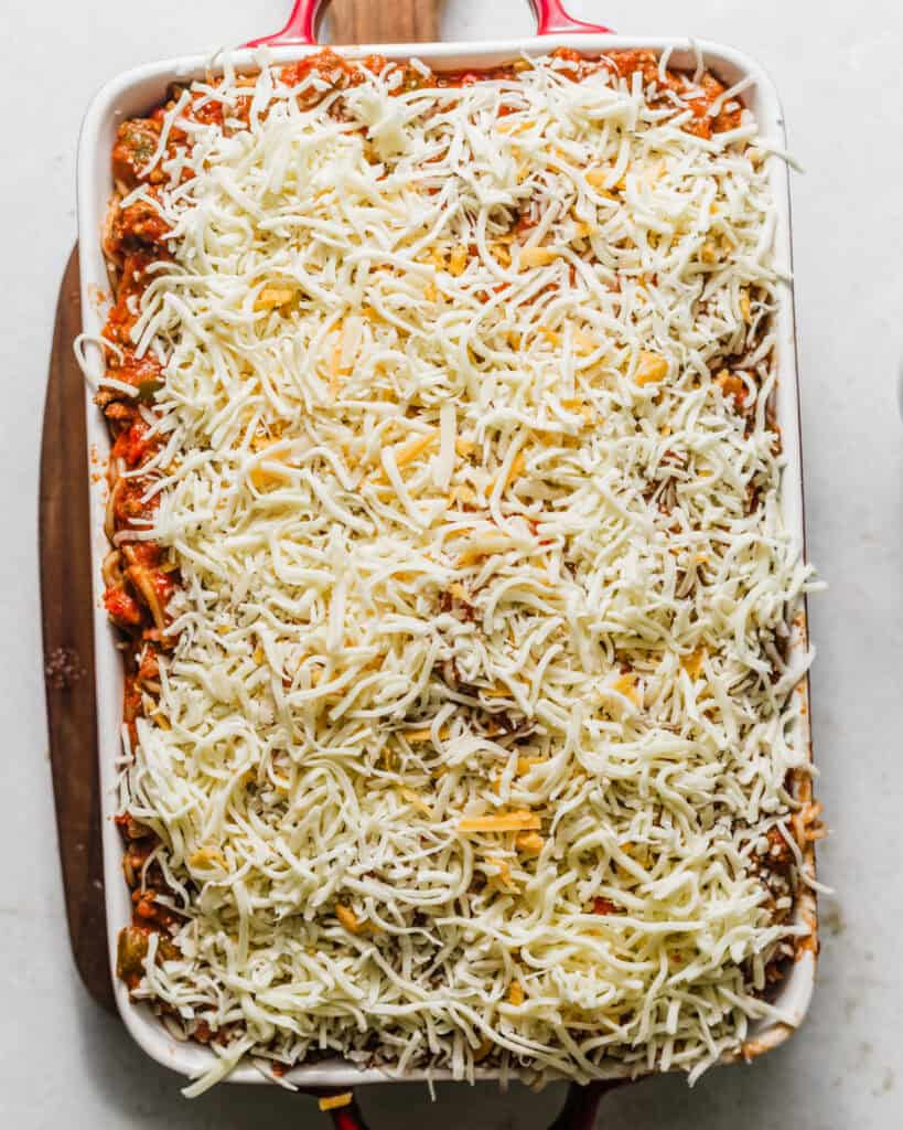 baked spaghetti assembled in a baking dish and topped with shredded cheese before baking.