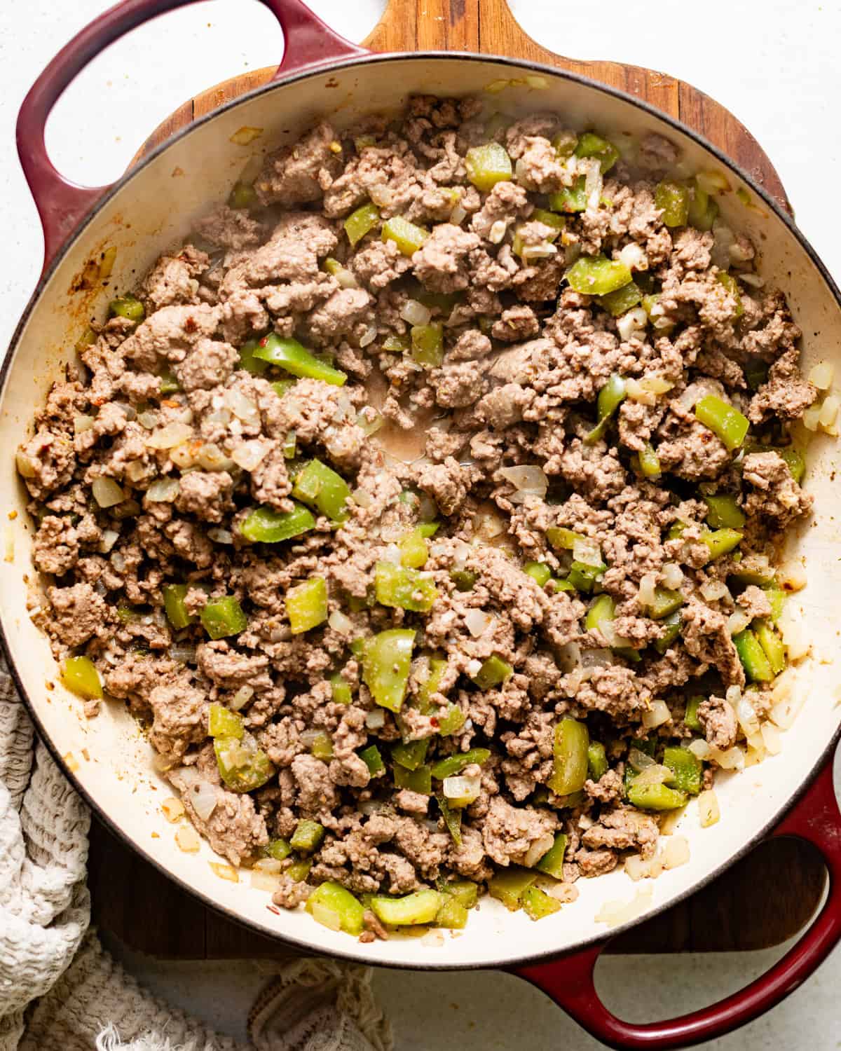 ground beef and italian sausage with green peppers, onions, and celery cooked in a pot.