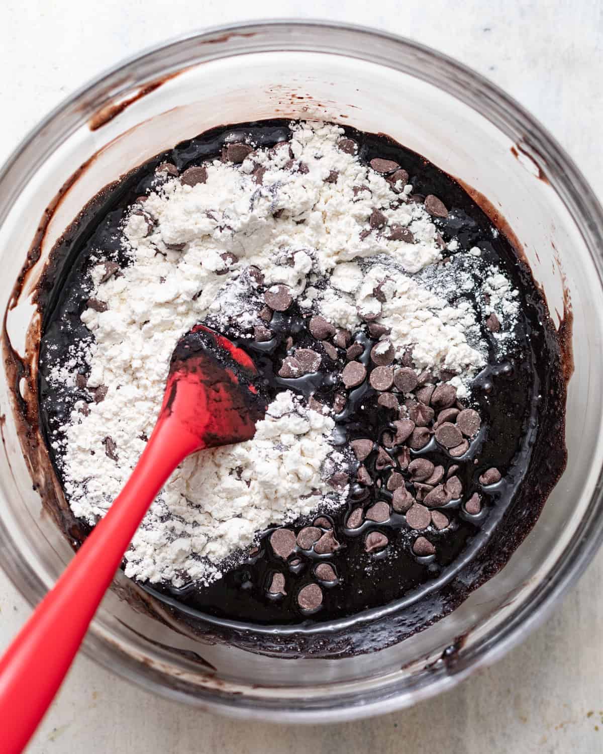 dry ingredients and chocolate chips being folded into the brownie batter.