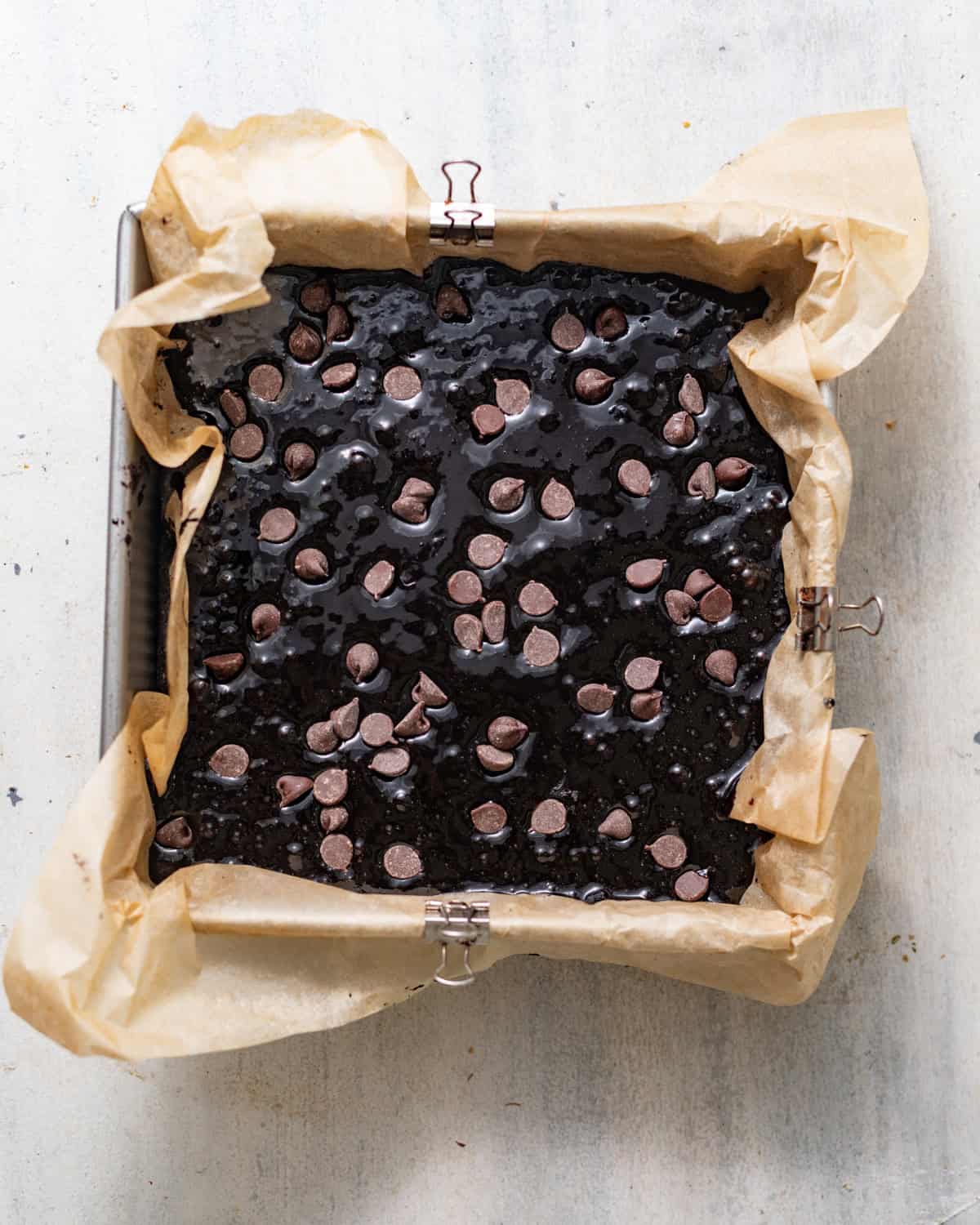 black cocoa brownie batter in a square baking pan lined with parchment paper.