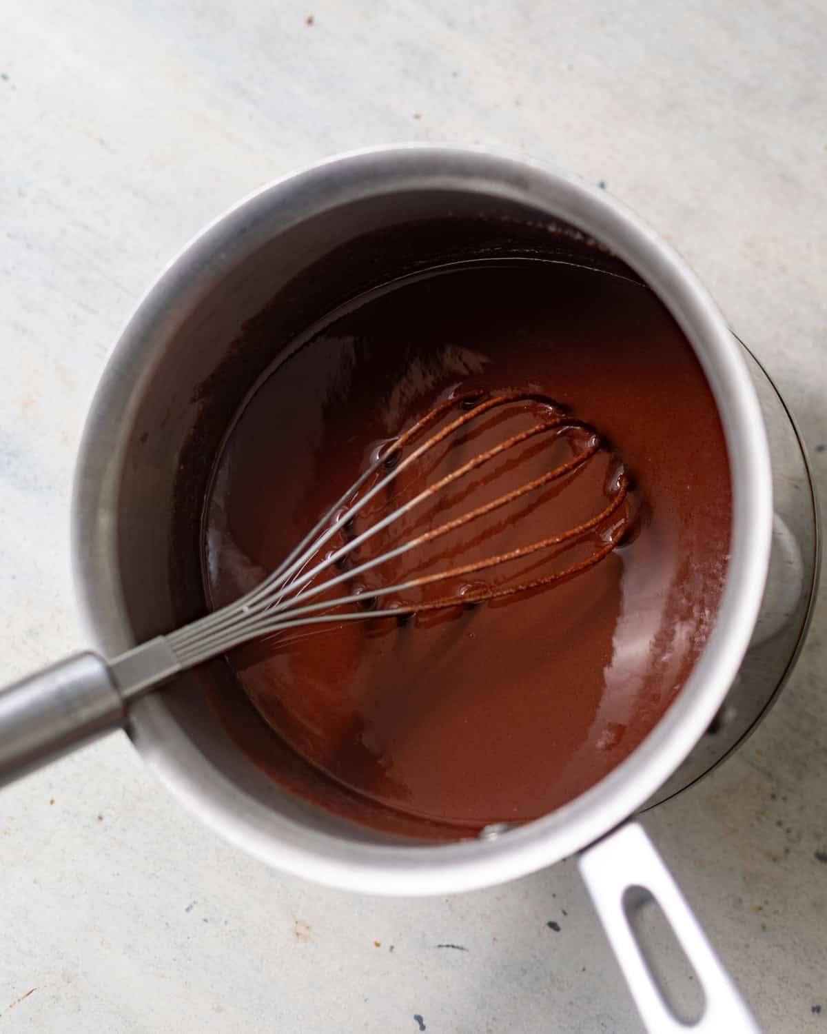 melted butter, sugar, oil, and chocolate chips in a saucepan with a whisk. 