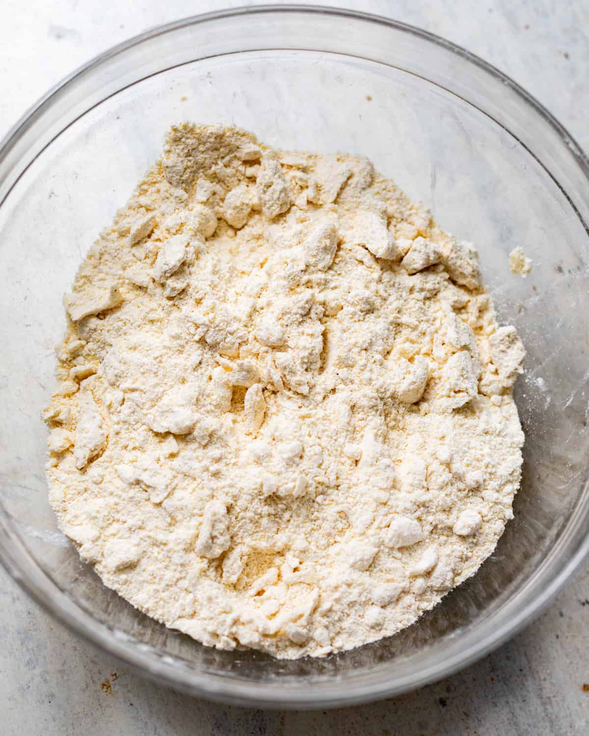 All-purpose flour, cornmeal, sugar, baking powder, baking soda, and kosher salt mixed with cold butter until crumbly, with small pieces of butter visible throughout.