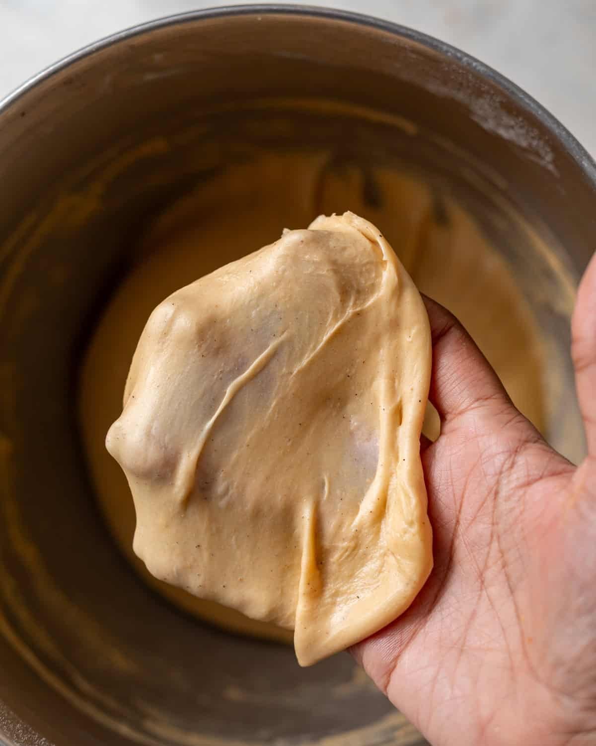 a stretched out piece of cinnamon roll dough to show readers what the windowpane test looks like.