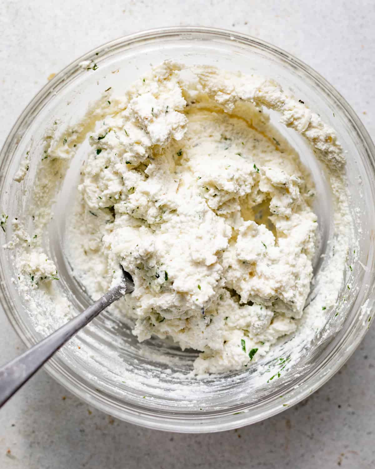 ricotta topping mixed together in a small bowl with fresh herbs.